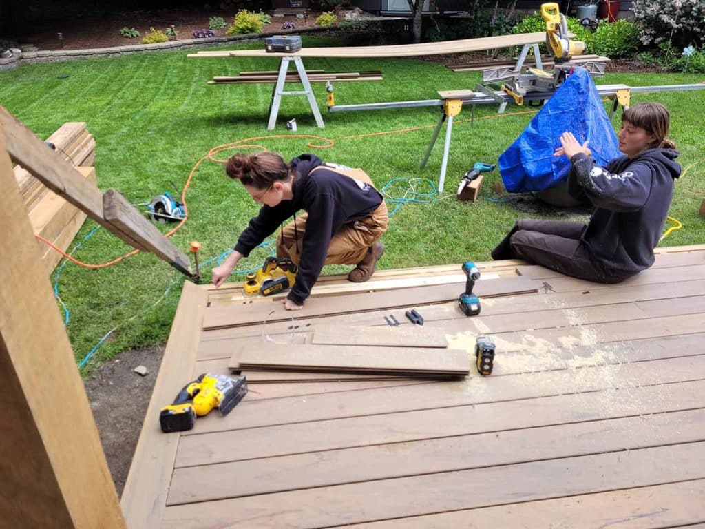 Two women working on deck construction.